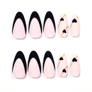 Detail of almond-shaped press-on nails with black French tips and heart pattern