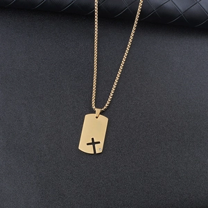 Detail of gold hollow cross dog tag pendant with small crystal on textured surface