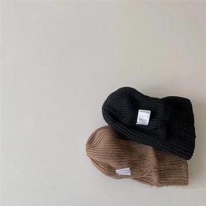 Close-up of ribbed knit texture on stylish black and brown winter beanies with labels