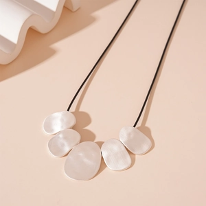 Detail of silver irregular oval pendants with matte brushed texture on a black rope