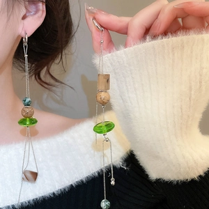 Close-up of tassel earrings with green glass beads, wooden texture beads and agate charms