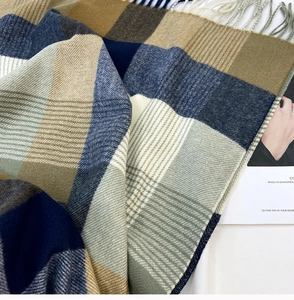 Close-up of soft tassel fringe and plaid knit texture on a winter cashmere scarf
