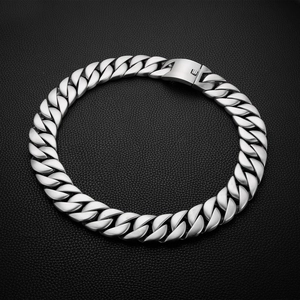 Detailed view of heavy silver stainless steel Cuban link chain on black leather background