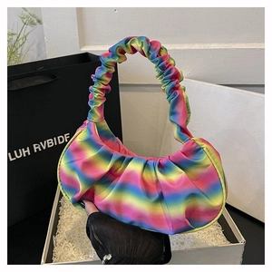 Macro detail of vibrant rainbow gradient pleated shoulder bag held with lace gloves