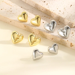 Detailed view of gold and silver heart studs with smooth and textured finishes on stone