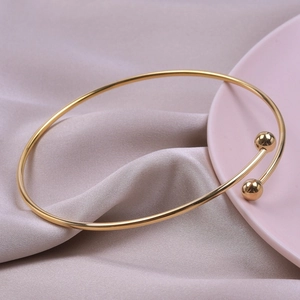 Close-up of minimalist golden stainless steel open cuff bracelet with double bead design