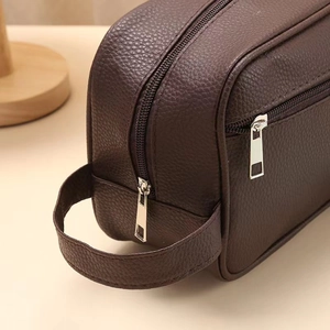 Detail of premium brown pebble grain leather texture and dual silver metal zippers