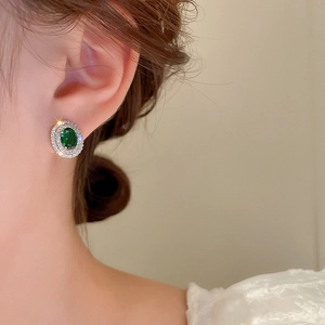 Detail of green oval gemstone earrings with micro-pave diamonds on a model