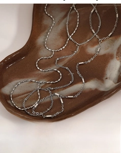 Silver multilayer metal chain necklaces elegantly displayed on a dark brown ceramic tray