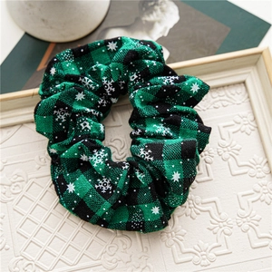 Close-up of green plaid Christmas scrunchie with snowflake patterns on white frame