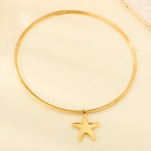 Close-up of golden starfish pendant on flat metal choker over beige silk fabric