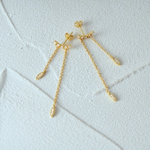 Detail of gold tassel earrings featuring small diamonds and sparkling teardrop pendants