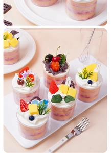 Detailed view of artificial mousse cake cups with realistic cream, berries, and mint leaves