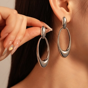 Retro metallic hollow oval drop earrings in silver finish worn by a fashion model