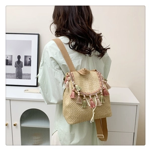 Detail of hand-woven straw bucket bag with colorful tassels and adjustable straps