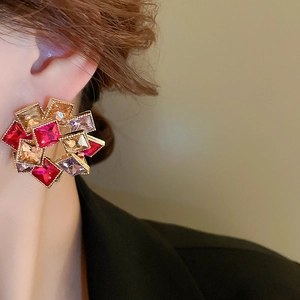 Détail de boucles d'oreilles géométriques avec cristaux colorés portées par un mannequin femme