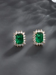Detail view of emerald green square earrings with white zircon halo on grey silk
