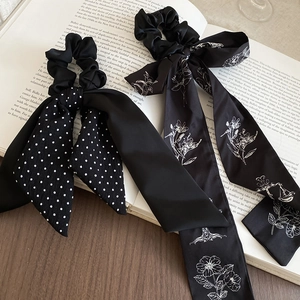 Close-up of black satin scrunchies with white polka dots and floral patterns with long ribbons