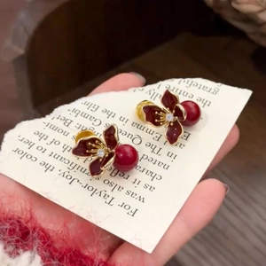 Détail d'une boucle d'oreille fleur rouge rétro avec perle sur papier vintage