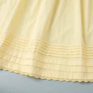 Detail of cream pleated A-line skirt hem featuring delicate lace trim and cotton texture