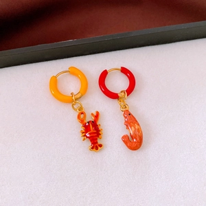 Detail of asymmetric titanium steel earrings featuring red shrimp and orange lobster charms