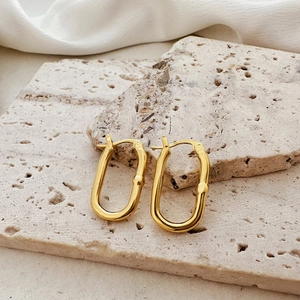 Macro shot of gold U-shaped chunky hoop earrings on a textured stone display
