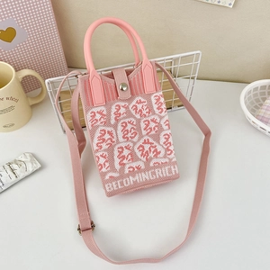 Detail of pink and white knitted phone bag with 'BECOMINGRICH' text and woven shoulder strap