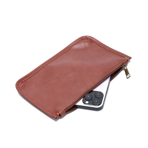 Gros plan d'une poche intérieure zippée en cuir marron avec un smartphone pour l'échelle