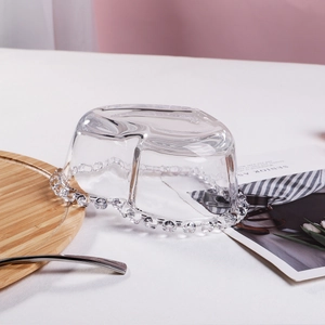 Detailed view of heart-shaped glass plate with beaded rim on a wooden serving tray