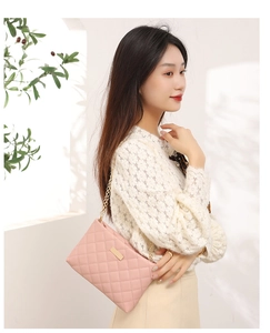 Pink quilted shoulder bag with gold chain strap shown on a model for scale and style