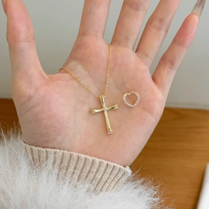 Detail of a gold cross pendant and heart charm with sparkling cubic zirconia accents
