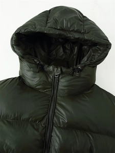 Detail of glossy dark green hooded puffer jacket with black elastic drawstrings and zipper