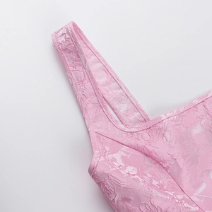 Gros plan sur la texture du tissu jacquard rose et le détail de la bretelle de la robe