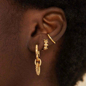 Close-up of golden multi-layered earrings set with textured hoop and spiral design