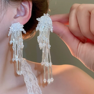 Close-up of elegant flower tassel earrings with white beads on a female model