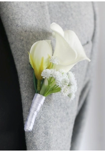 Close-up of white calla lily boutonniere with baby's breath on a grey suit lapel