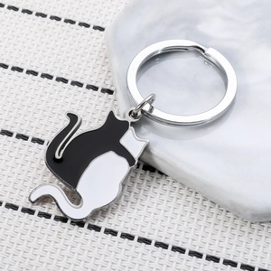 Minimalist black and white cat keychain made of metal and enamel on woven background
