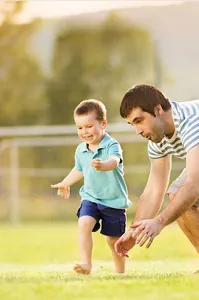 Father and son play with a 6cm blue high-elastic mini basketball toy on a green lawn