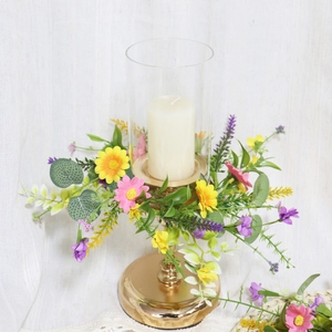 Macro shot of faux daisy and lavender floral ring around a gold candle holder base