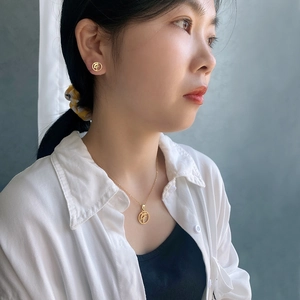 Detailed view of a gold titanium steel necklace and stud earrings set on a female model