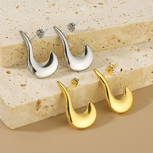 Macro shot of oval hollow earrings in gold and silver finish on textured stone