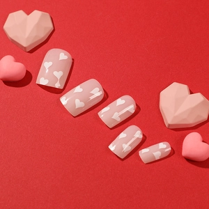 Press-on nails in nude pink with white heart patterns for Valentine's Day style