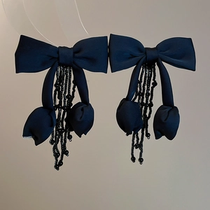 Detail of elegant black fabric bow earrings with delicate beaded tassel fringe