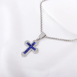 Close-up of silver cross pendant featuring intricate blue and clear gemstone settings