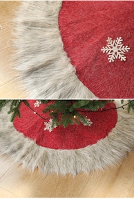 Close-up of red felt Christmas tree skirt with grey plush border and white snowflakes