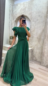 Detail of elegant dark green pleated evening dress featuring layered ruffle cap sleeves