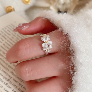 Close-up of matte silver flower ring with gold stamens on a textured cozy background