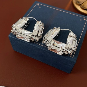 Gros plan de boucles d'oreilles rectangulaires en argent avec cristaux sur boîte bleue