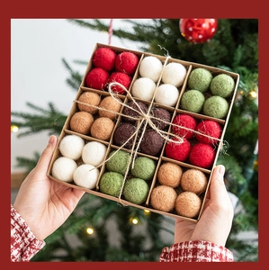 Detail of wool felt Christmas ornament balls in a gift box with a rustic holiday setting
