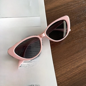 Detailed close-up of pink cat eye sunglasses on vintage newspaper for a retro look